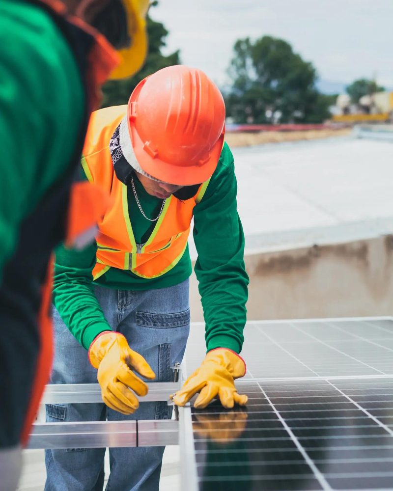 2 Workers with green and orange uniform installing a solar panel